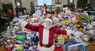 Santa in front of mountain of toys