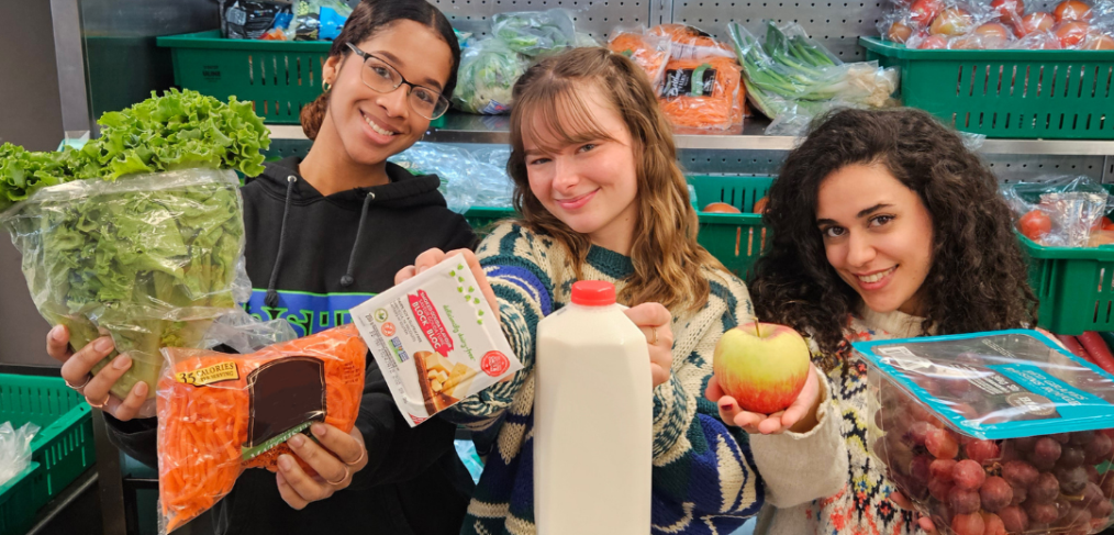 Three girls holding food items, posing for a picture