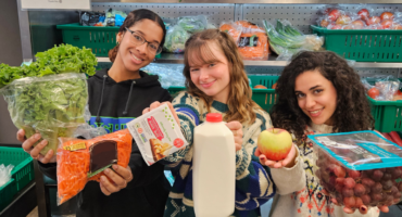 Three girls holding food items, posing for a picture
