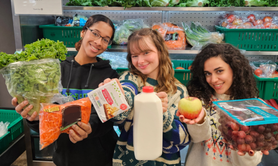 Three girls holding food items, posing for a picture